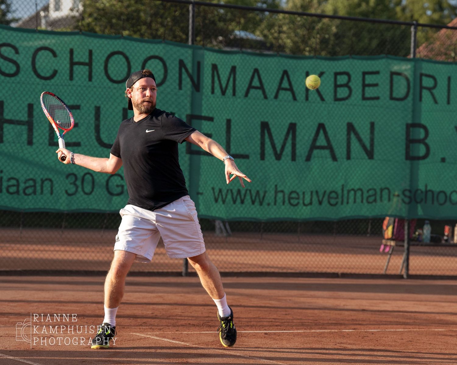 Actiefoto's van gravel tennistoernooi met spelers in actie, dubbelspel, toeschouwers en zomerse sfeer rond de baan.