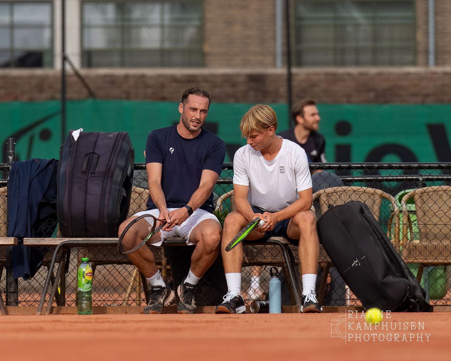 Actiefoto's van de vrijdagavond van een gravel tennistoernooi met spelers in actie, dubbelspel, toeschouwers en zomerse sfeer rond de baan.