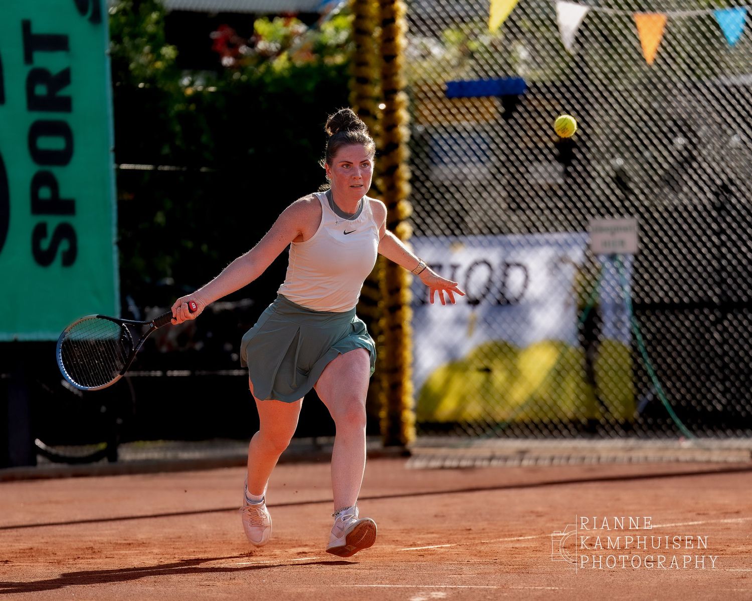 Actiefoto's van gravel tennistoernooi met spelers in actie, dubbelspel, toeschouwers en zomerse sfeer rond de baan.