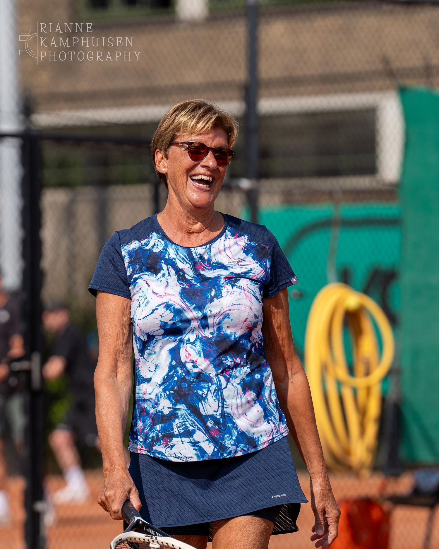 Actiefoto's van gravel tennistoernooi met spelers in actie, dubbelspel, toeschouwers en zomerse sfeer rond de baan.