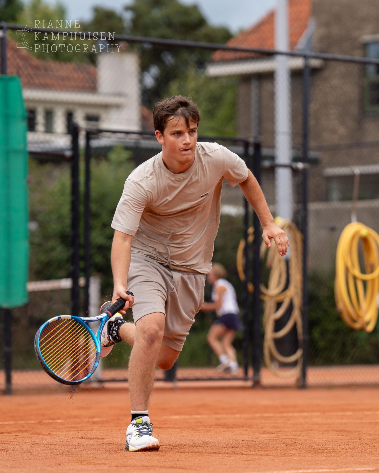 Actiefoto's van gravel tennistoernooi met spelers in actie, dubbelspel, toeschouwers en zomerse sfeer rond de baan.