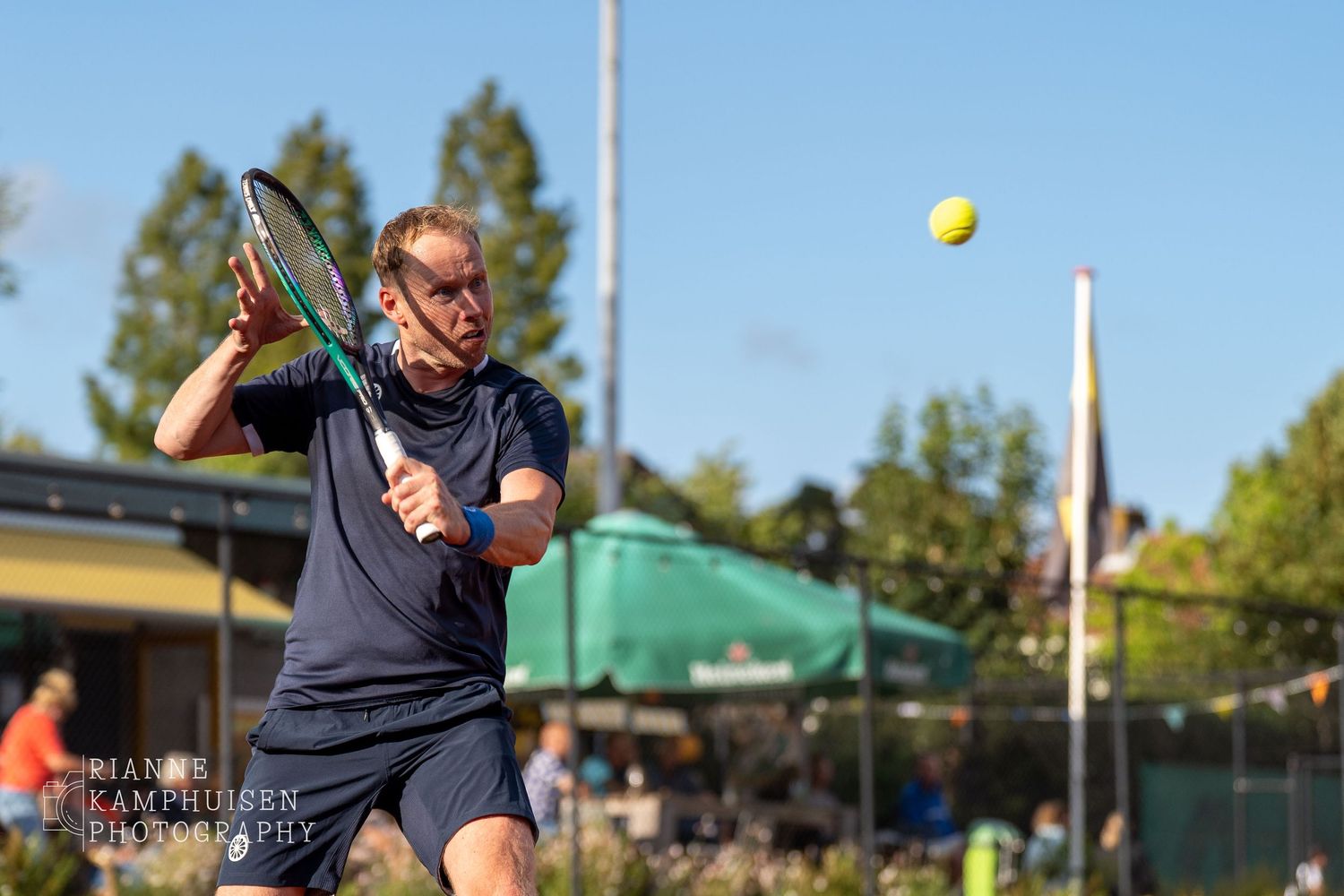 Actiefoto's van gravel tennistoernooi met spelers in actie, dubbelspel, toeschouwers en zomerse sfeer rond de baan.