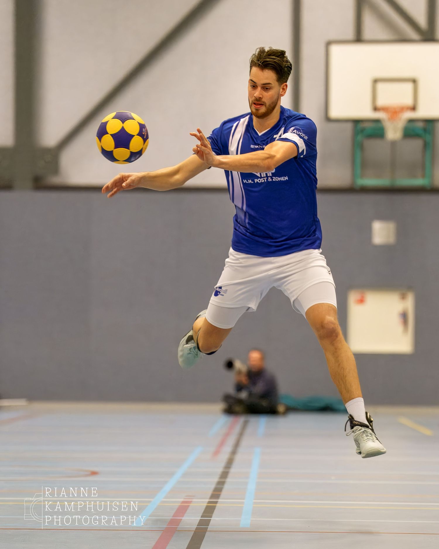 Korfbalspeler hangt in de lucht terwijl hij probeert om de bal binnen de lijnen te houden.