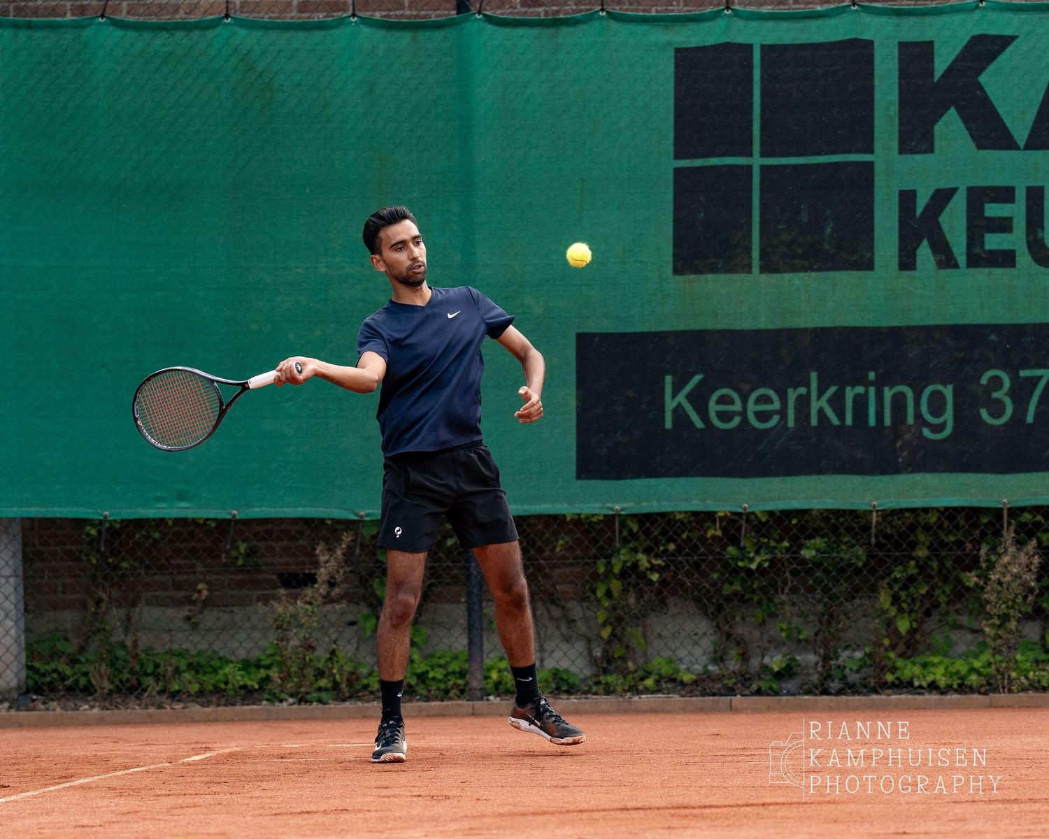 Actiefoto's van de vrijdagavond van een gravel tennistoernooi met spelers in actie, dubbelspel, toeschouwers en zomerse sfeer rond de baan.