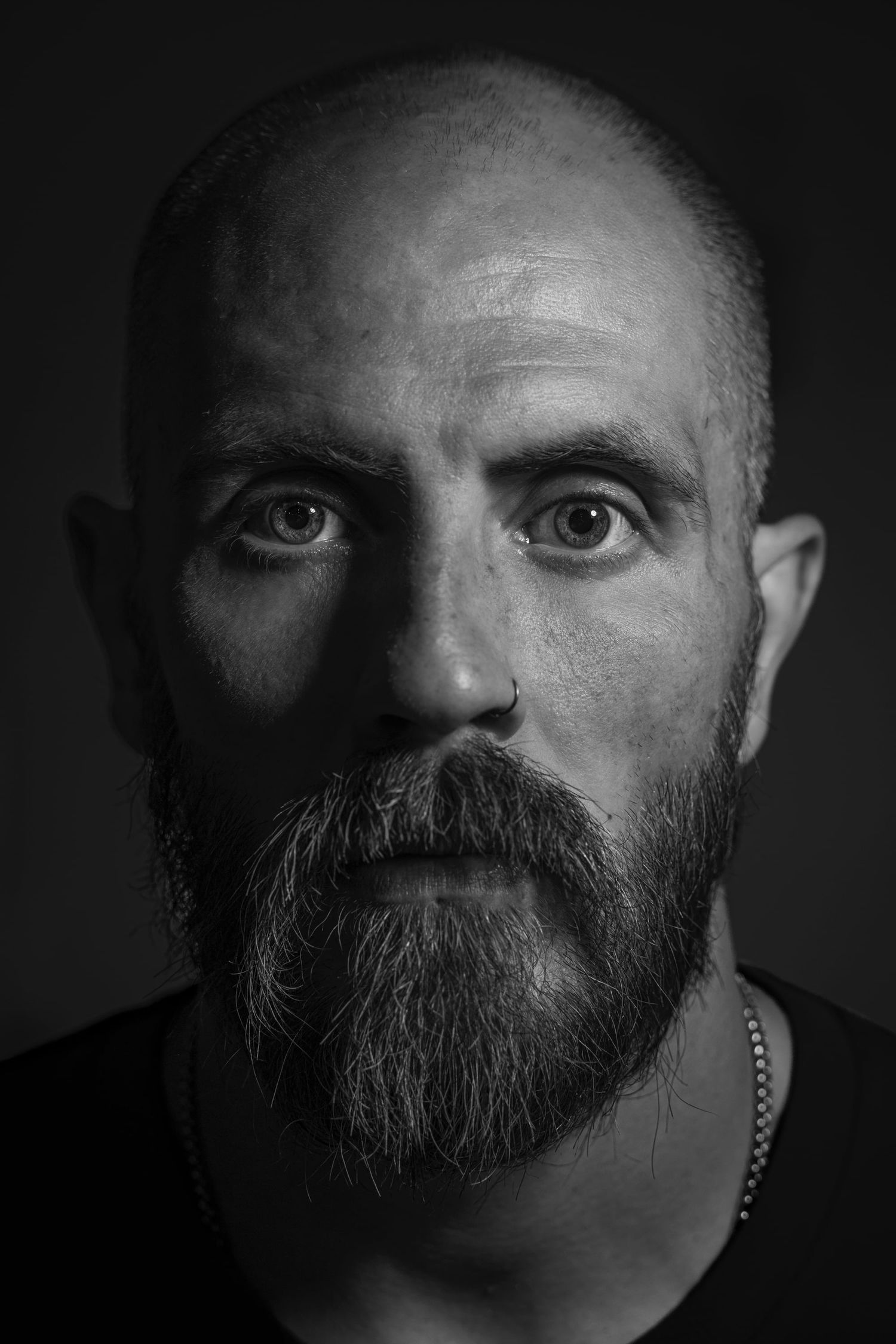 Dramatic black and white close-up portrait series showing a bearded man's face emerging from shadows against dark background.