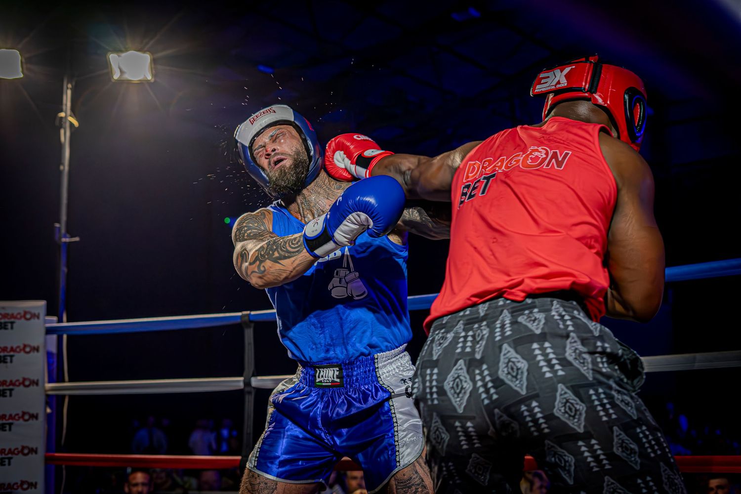 Boxing match action sequence showing fighters exchanging punches in a dimly lit ring during high intensity combat.