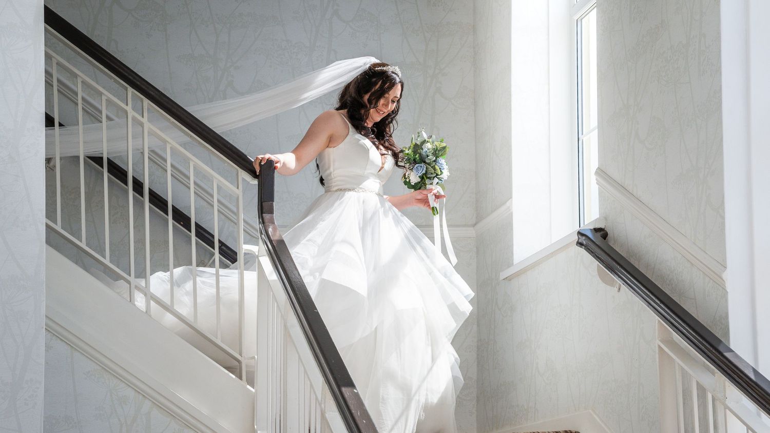 Wedding couple walking down modern staircase with artistic lighting.