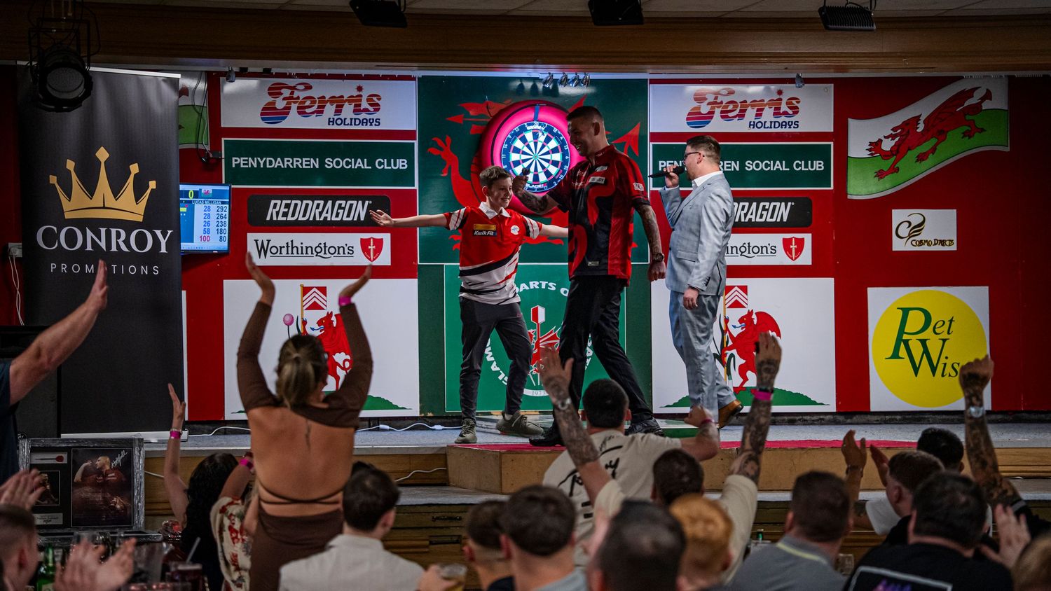 Sports fans cheer and celebrate in a crowded bar with TV screens and decorations on the walls.