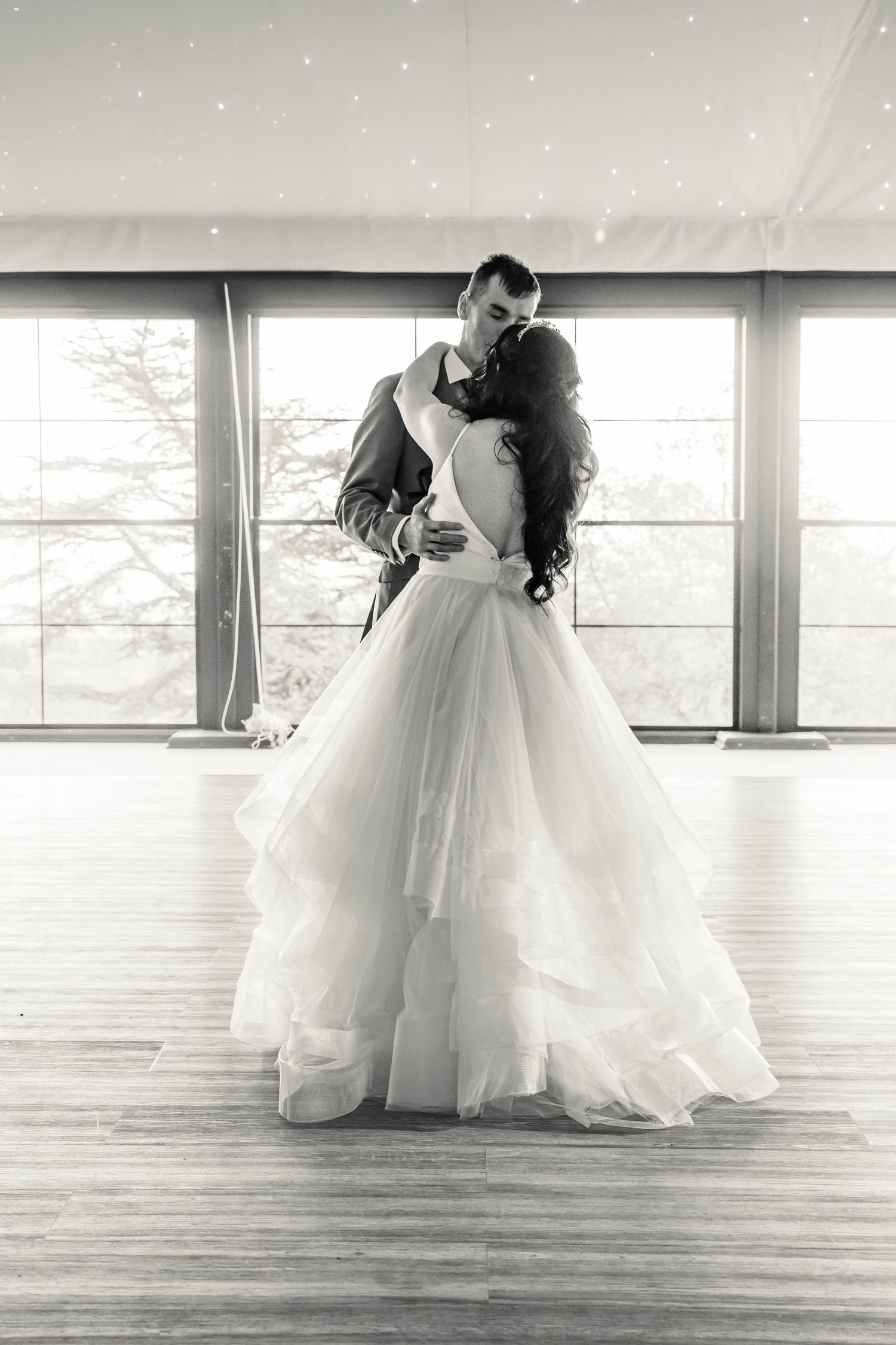 Romantic black and white dance sequence on hardwood floor with flowing wedding dress.
