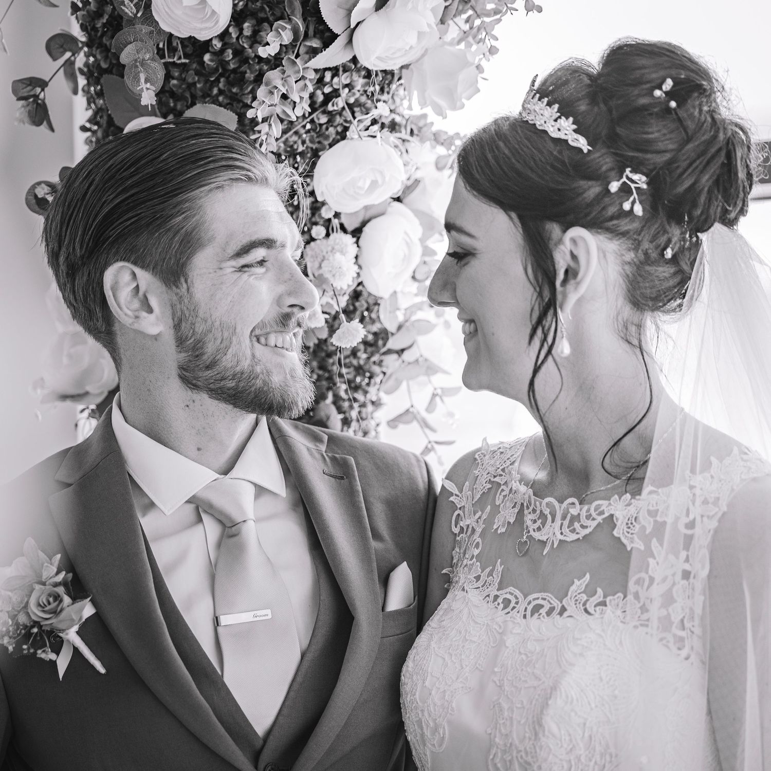 Black and white romantic wedding portraits with floral backdrop and intimate moments.