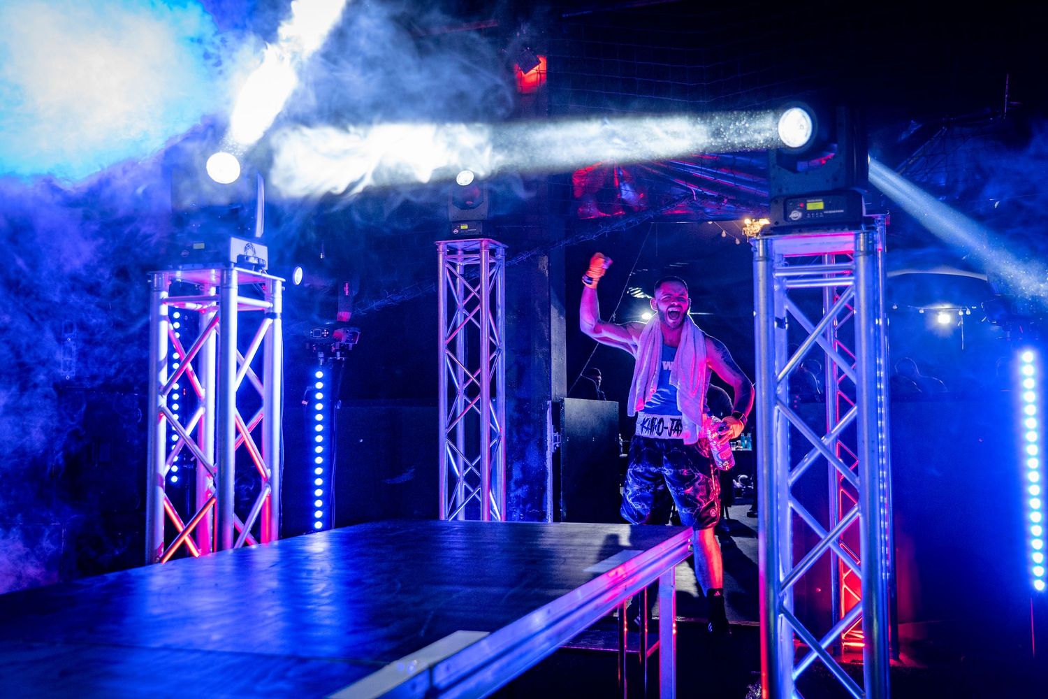 Stage lighting equipment setup with blue spotlights illuminating metal truss structures at a performance venue.