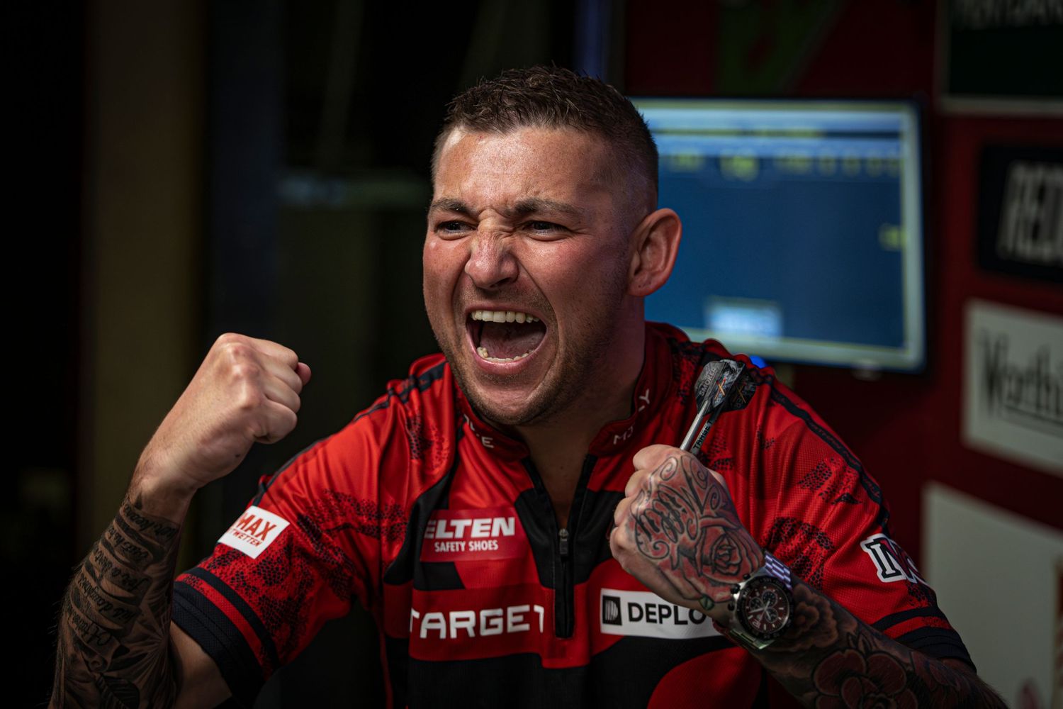 A person wearing a red Target branded shirt reacts with laughter while sitting indoors.