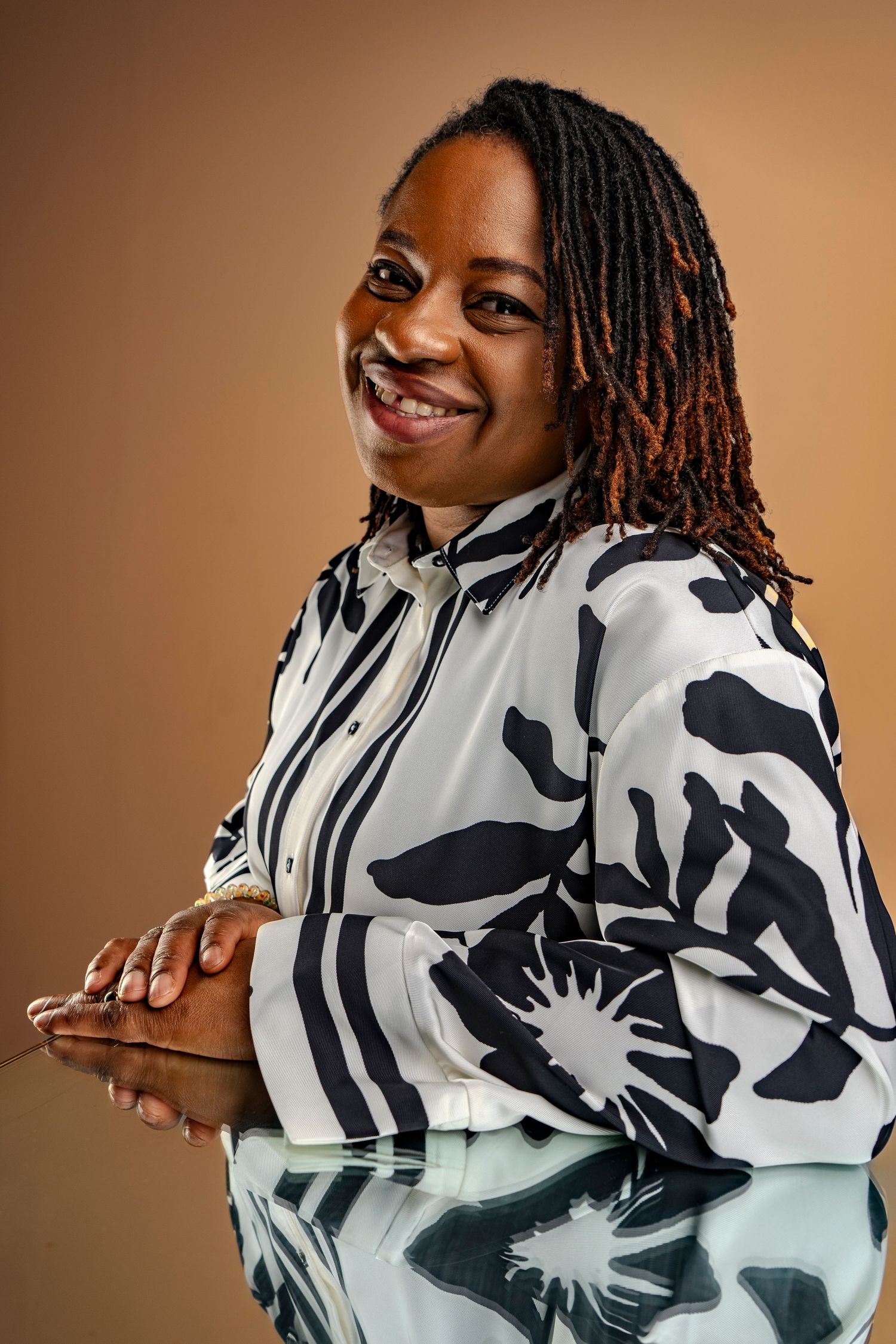 Studio portrait series showing someone in a black and white floral pattern jacket against brown background.