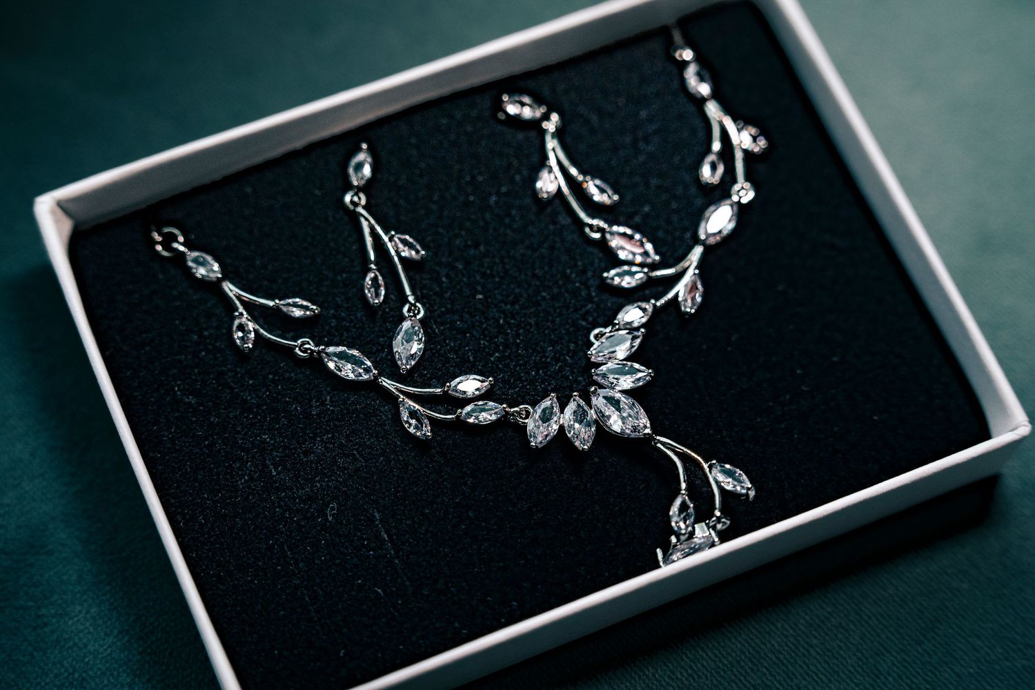 Delicate silver jewelry pieces arranged in black display boxes.