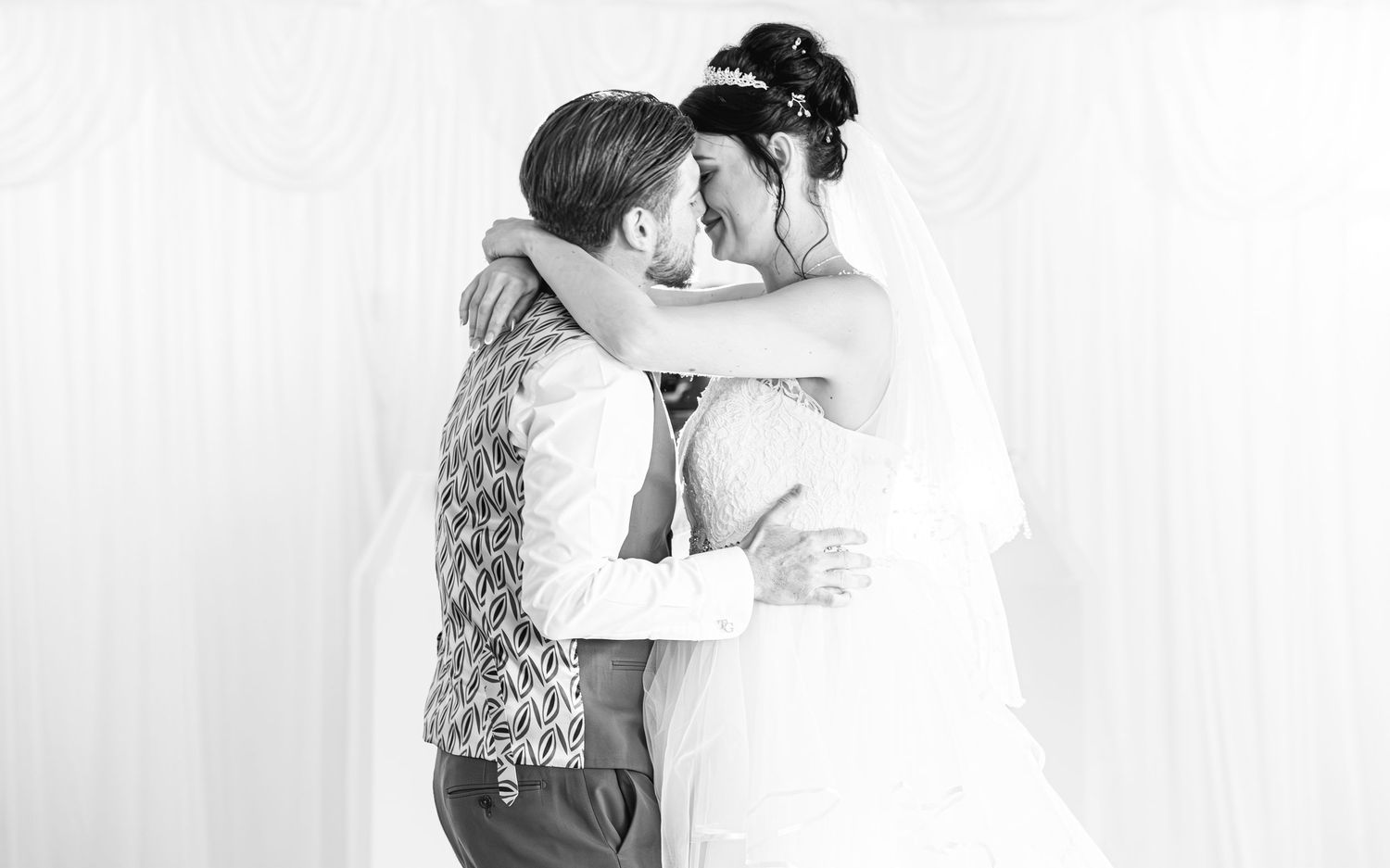 A romantic wedding embrace captured in black and white photography.