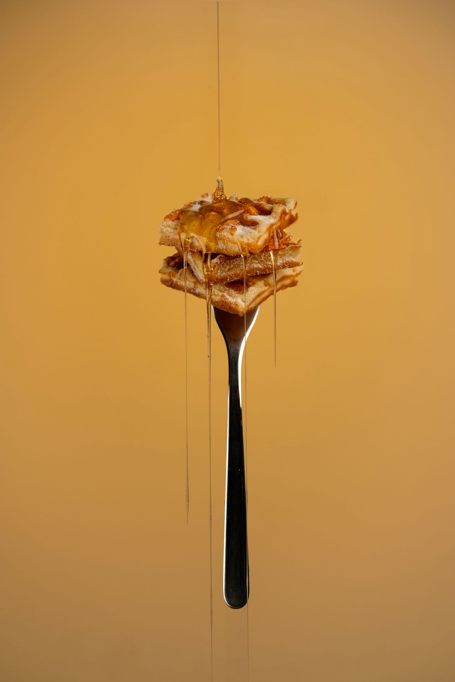 Crown-shaped water splash on minimalist amber background captured with high-speed photography.
