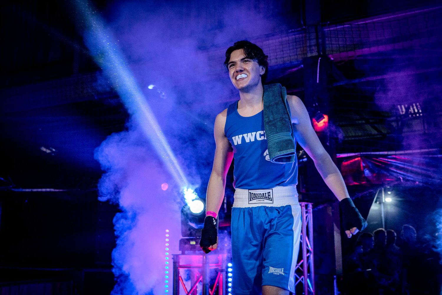 Concert performer on stage with dramatic blue lighting and smoke effects.
