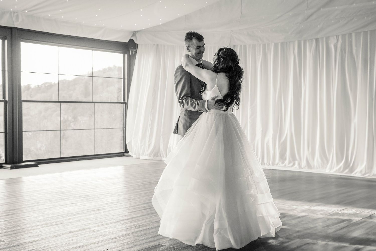 Elegant indoor wedding setting with white drapes and natural window lighting.