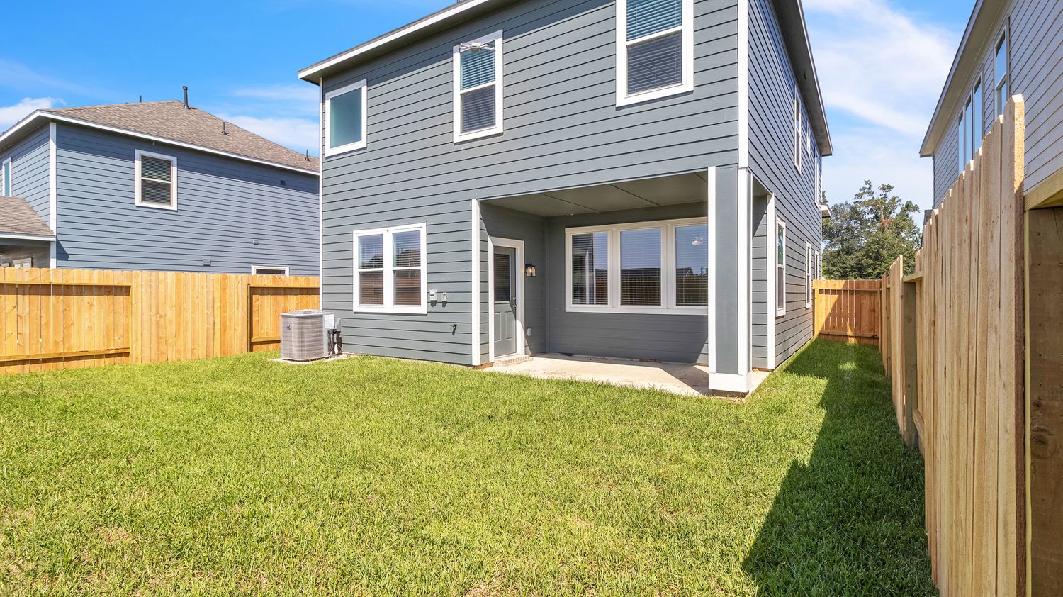 A 360-degree panoramic view of suburban homes with gray siding and wooden privacy fences under a blue sky.