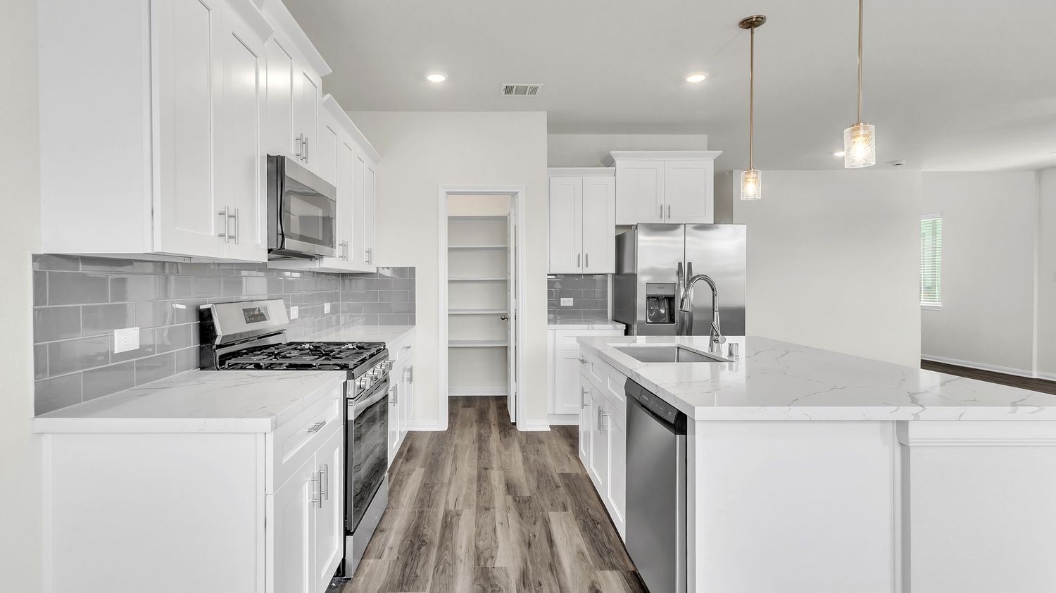 Modern apartment interior with open concept design featuring white walls, wood flooring and recessed lighting.