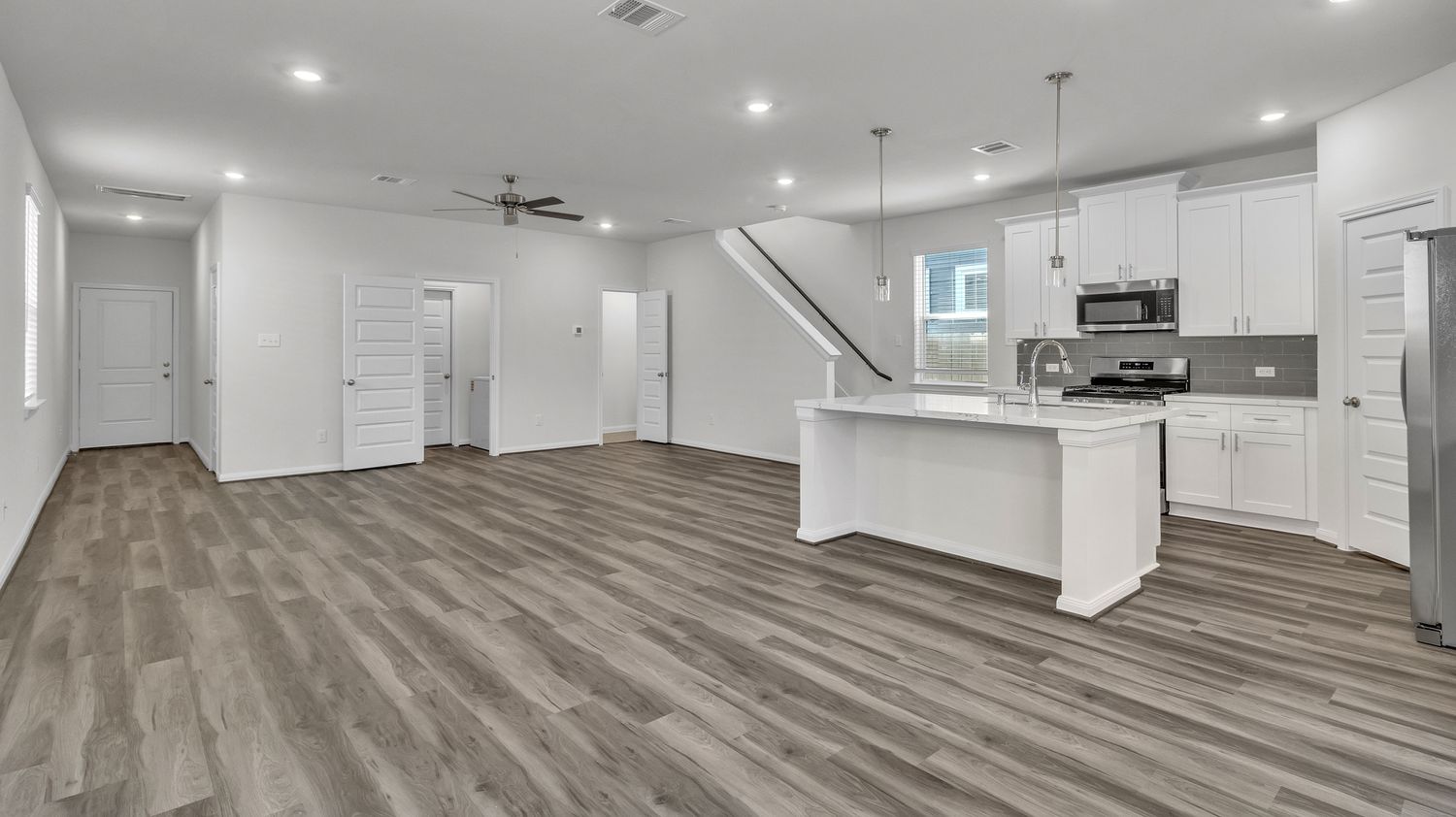 Open concept living space with gray luxury vinyl plank flooring and recessed lighting throughout.