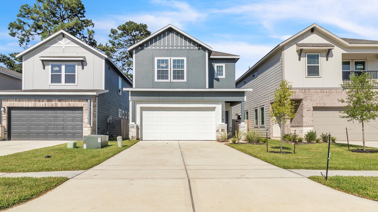 Modern gray and white craftsman style house with two-car garage and concrete driveway in a residential neighborhood.