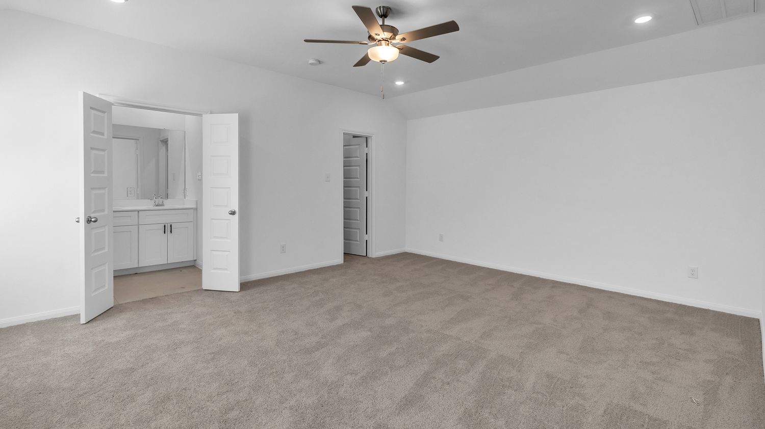 A freshly renovated empty white interior space showcases crown molding, recessed lighting and beige carpeted flooring.