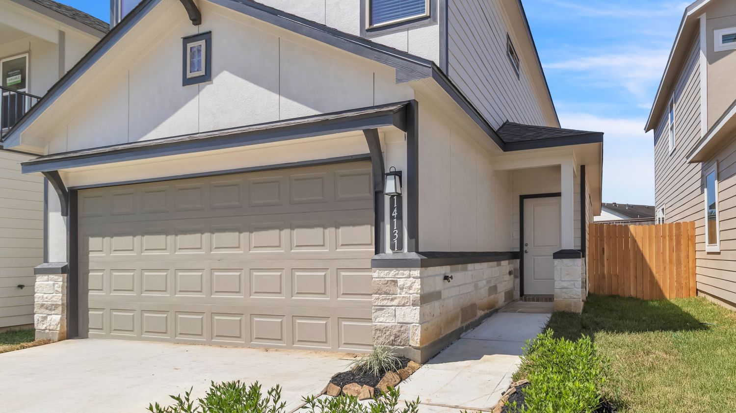 Residential garage doors and driveways show exterior views of modern suburban homes against a blue sky backdrop.