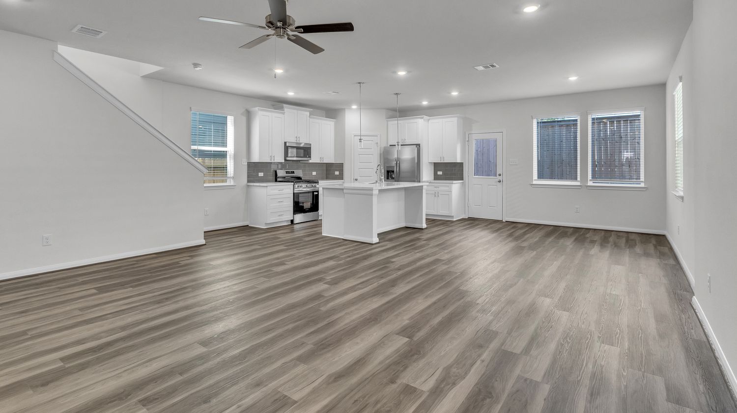 A newly renovated open concept living space with gray walls and a rich brown hardwood floor stretches across multiple rooms.