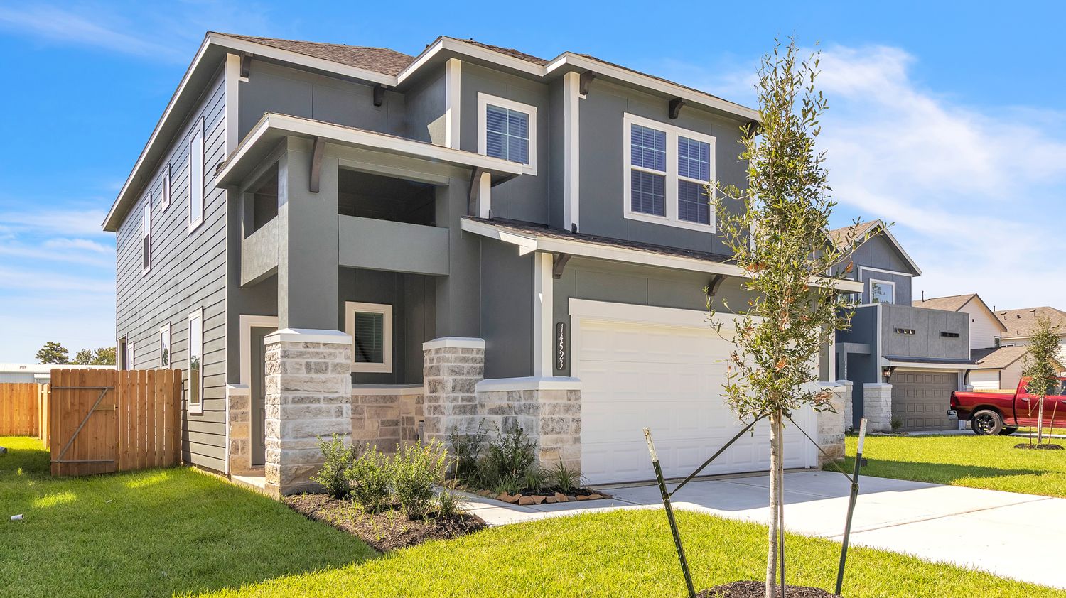 Home exterior photo showing a row of modern suburban houses with gray siding and green lawns under blue sky.