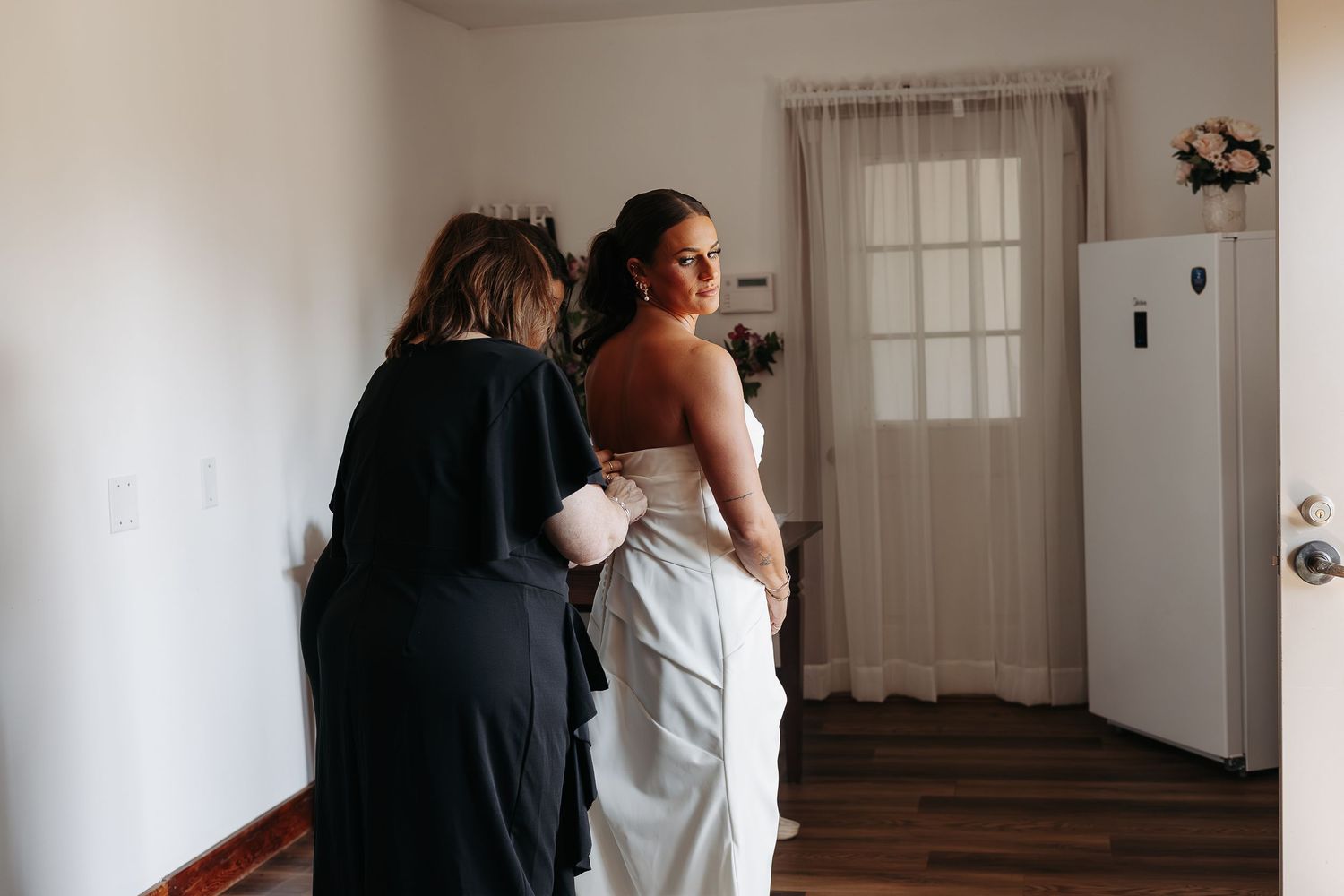 Mother of bride buttoning wedding gown