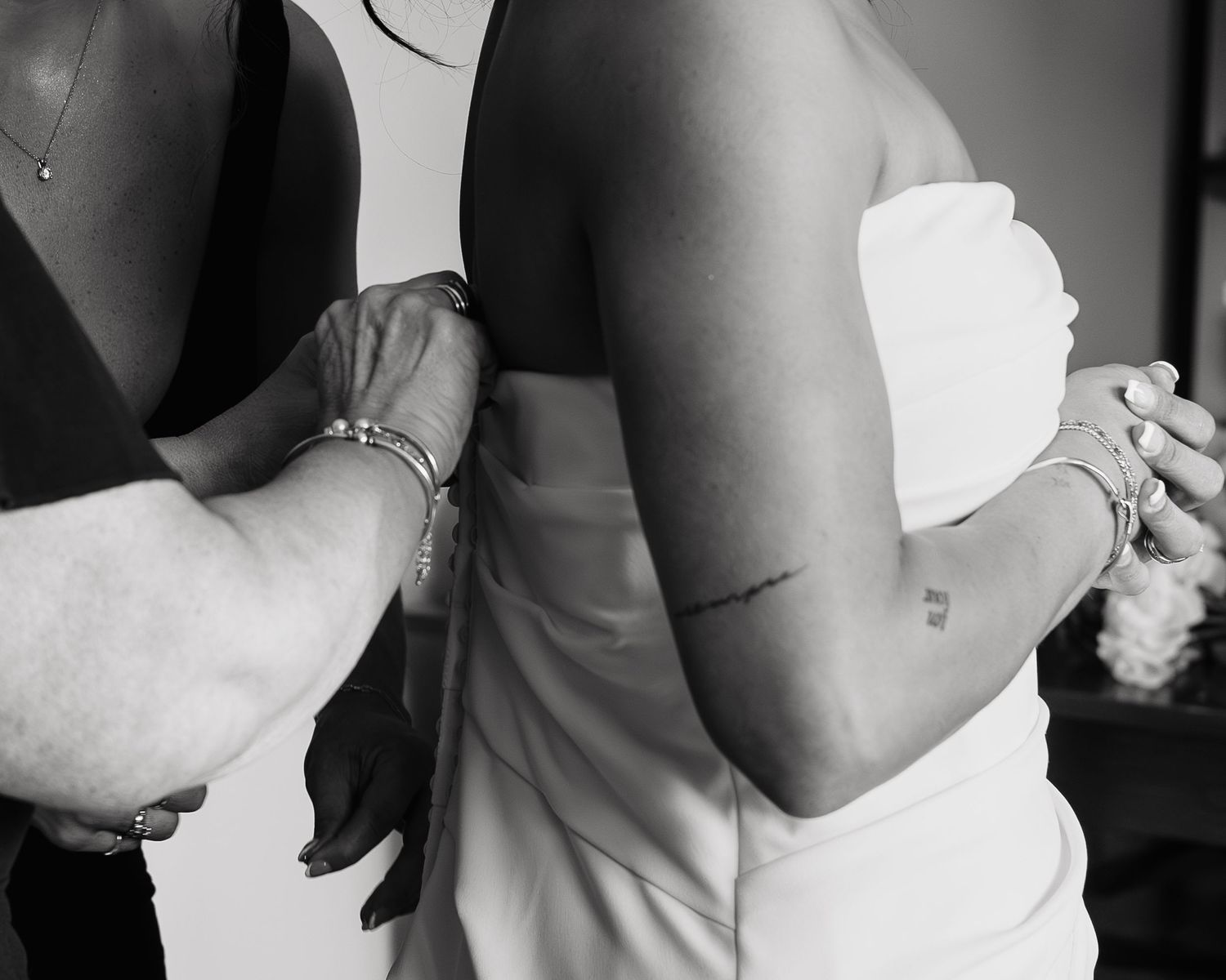 Mother of bride buttoning wedding gown