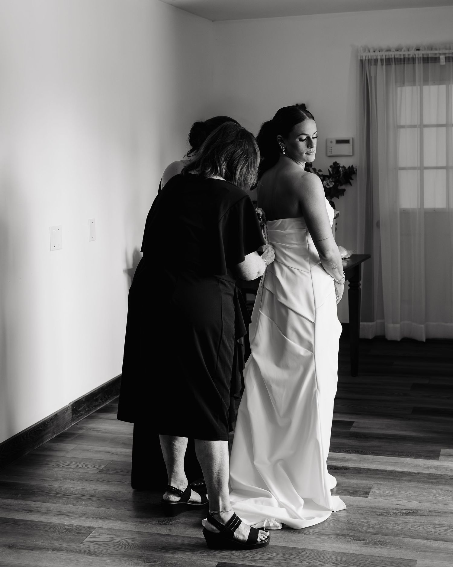 Mother of bride buttoning wedding gown