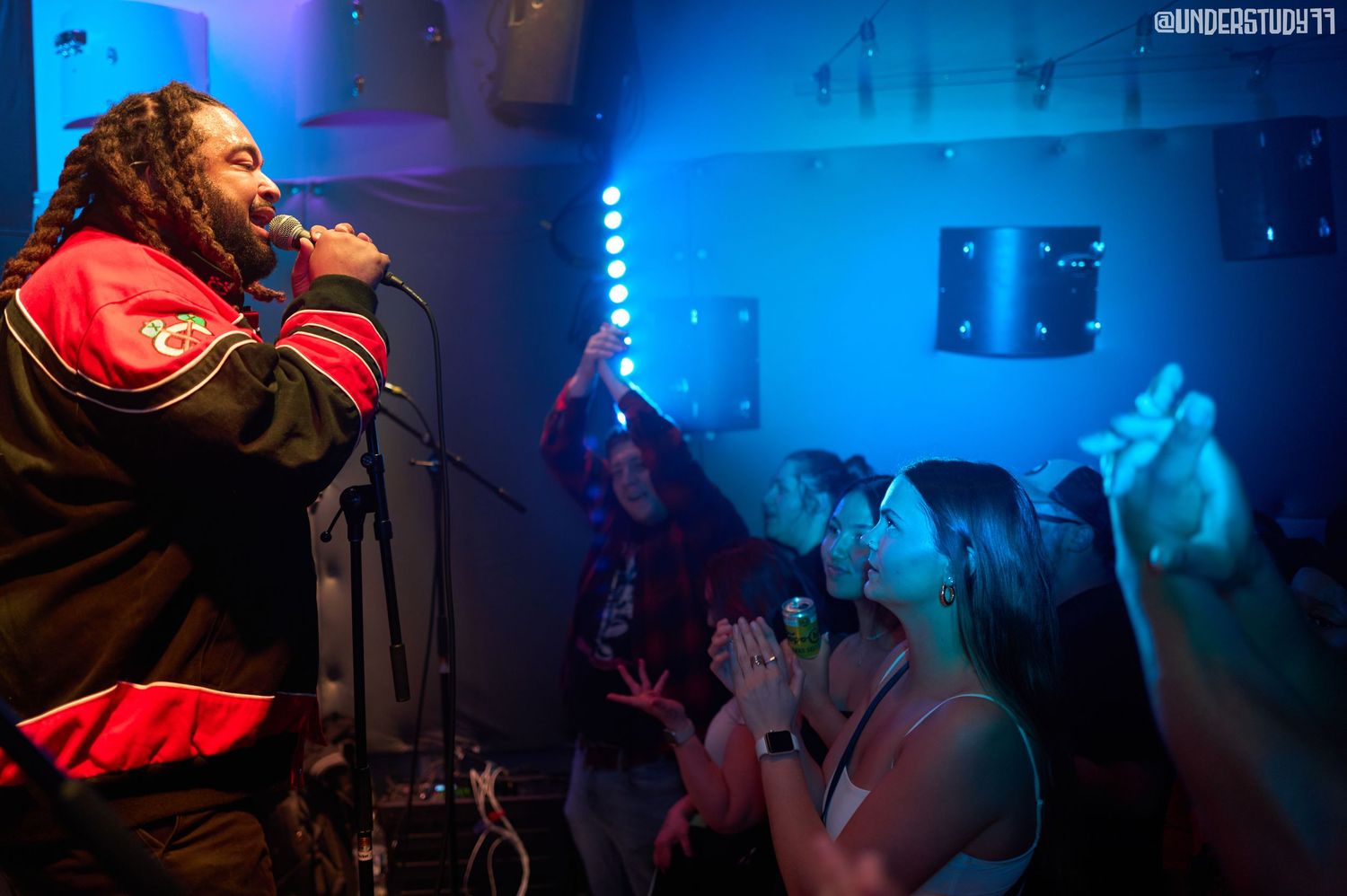 Fluorescents perform live at a small DC venue, blue stage lighting washing over the energetic crowd.