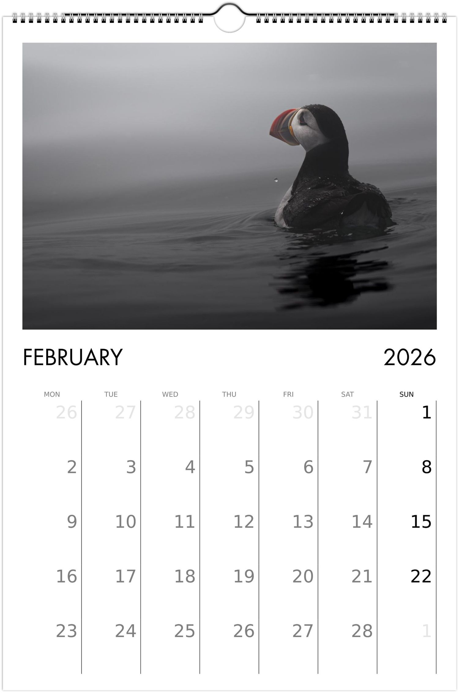 A black and white calendar page for February 2026 features artistic photographs of puffins swimming in dark waters.