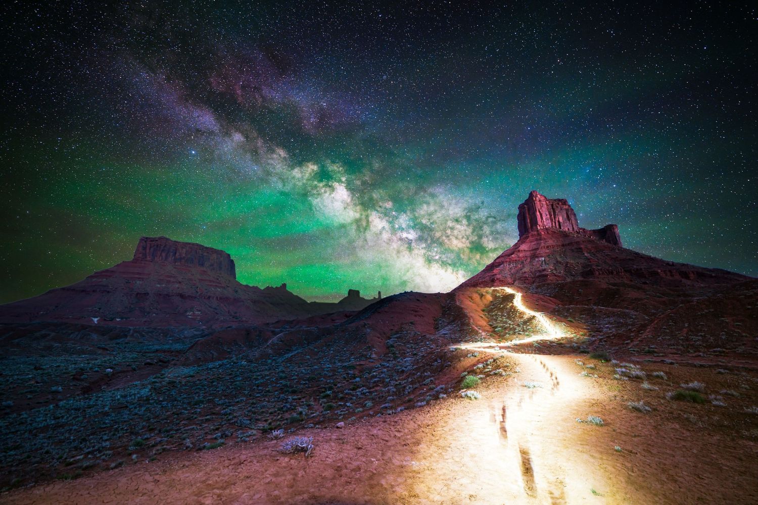 Milky Way arcs over Ida Gulch, Utah, with a glowing trail leading into the desert night sky.