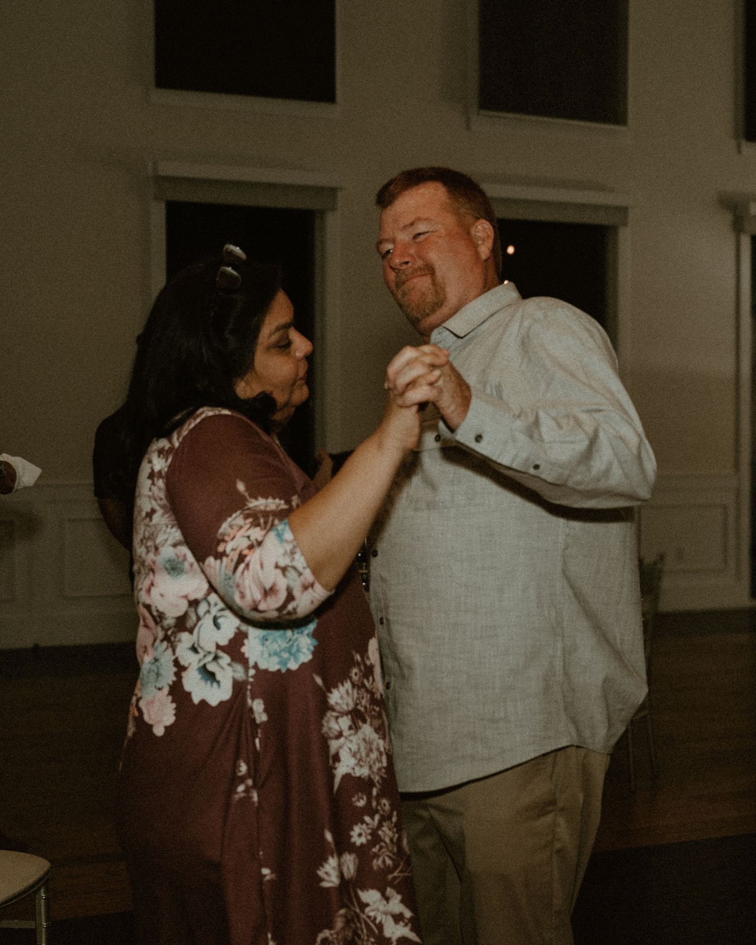 Couple sharing a romantic dance together in dim lighting at wedding reception.