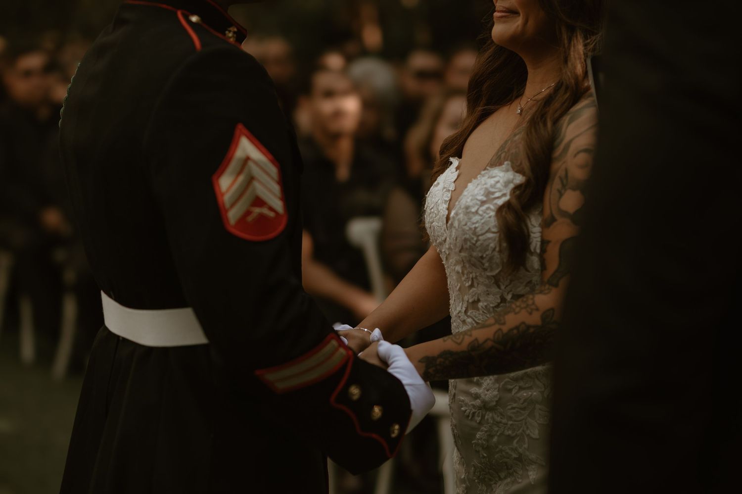 Military wedding ceremony with bride in lace gown exchanging vows outdoors.
