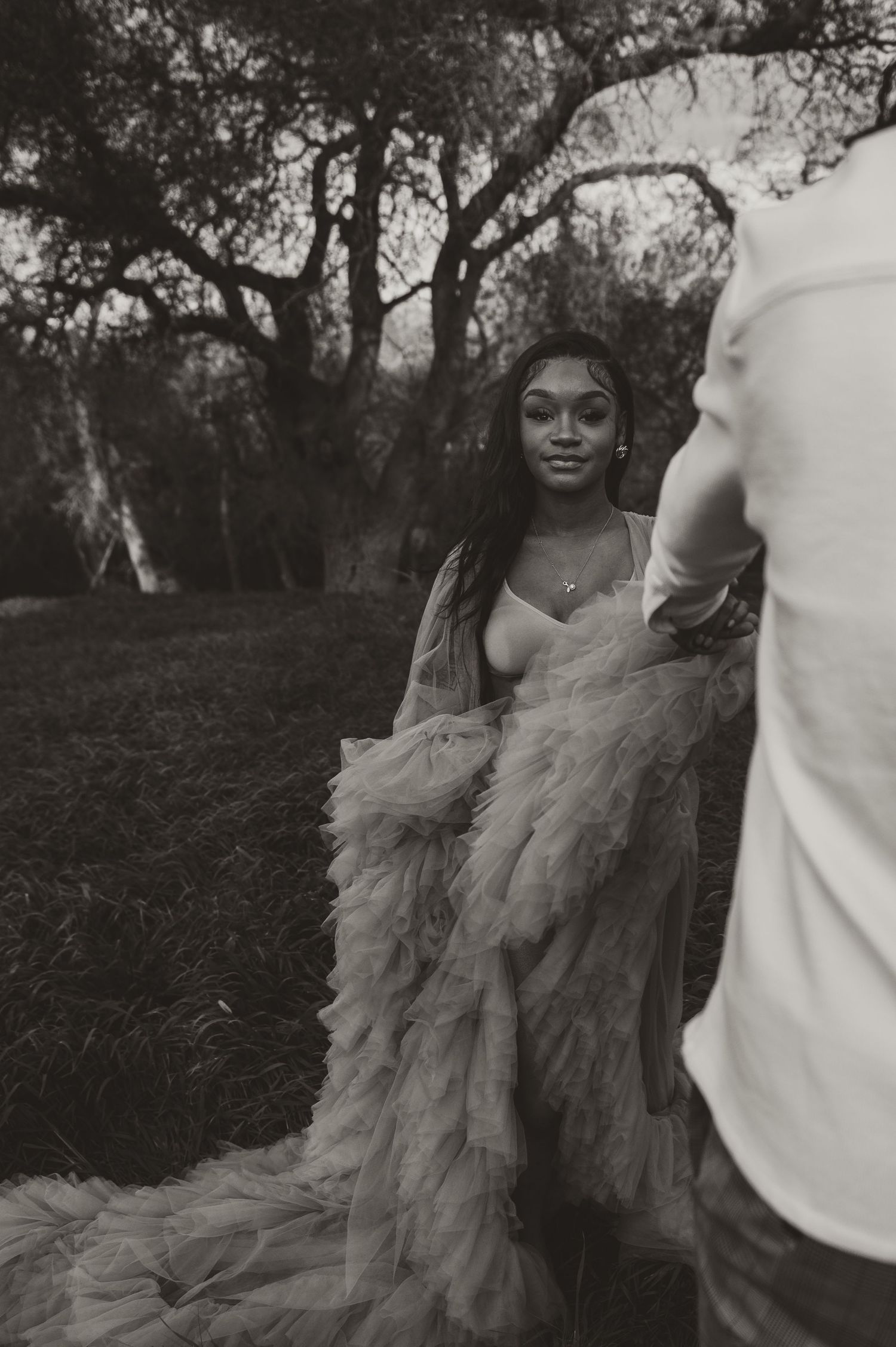Black and white outdoor portrait featuring dramatic tulle dress under trees.