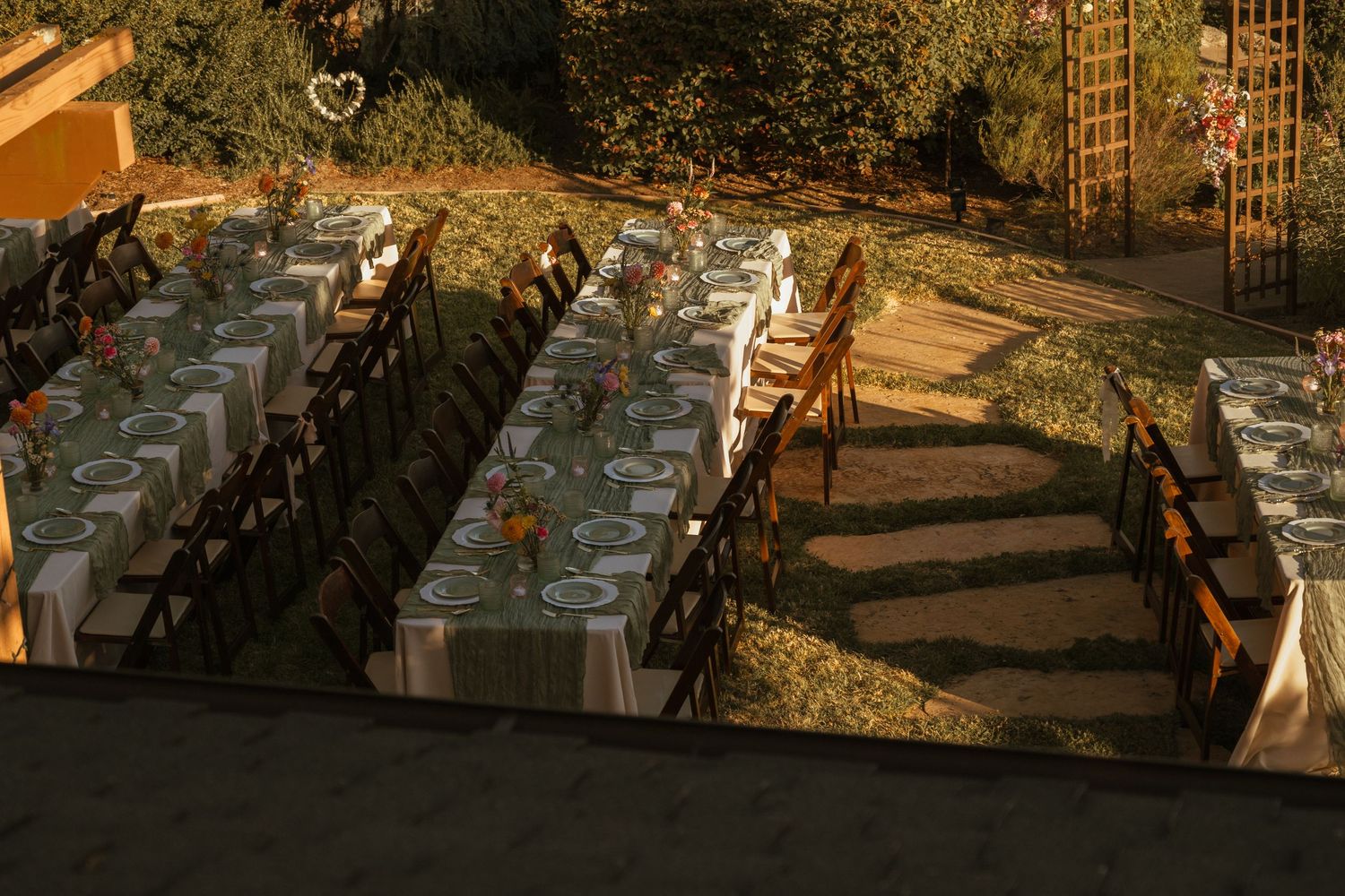 Elegant outdoor wedding reception setup with long tables and chairs at sunset.
