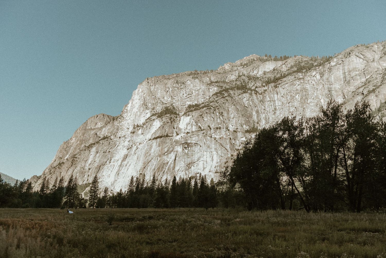 Panoramic view of majestic granite cliffs and mountains under clear blue skies.