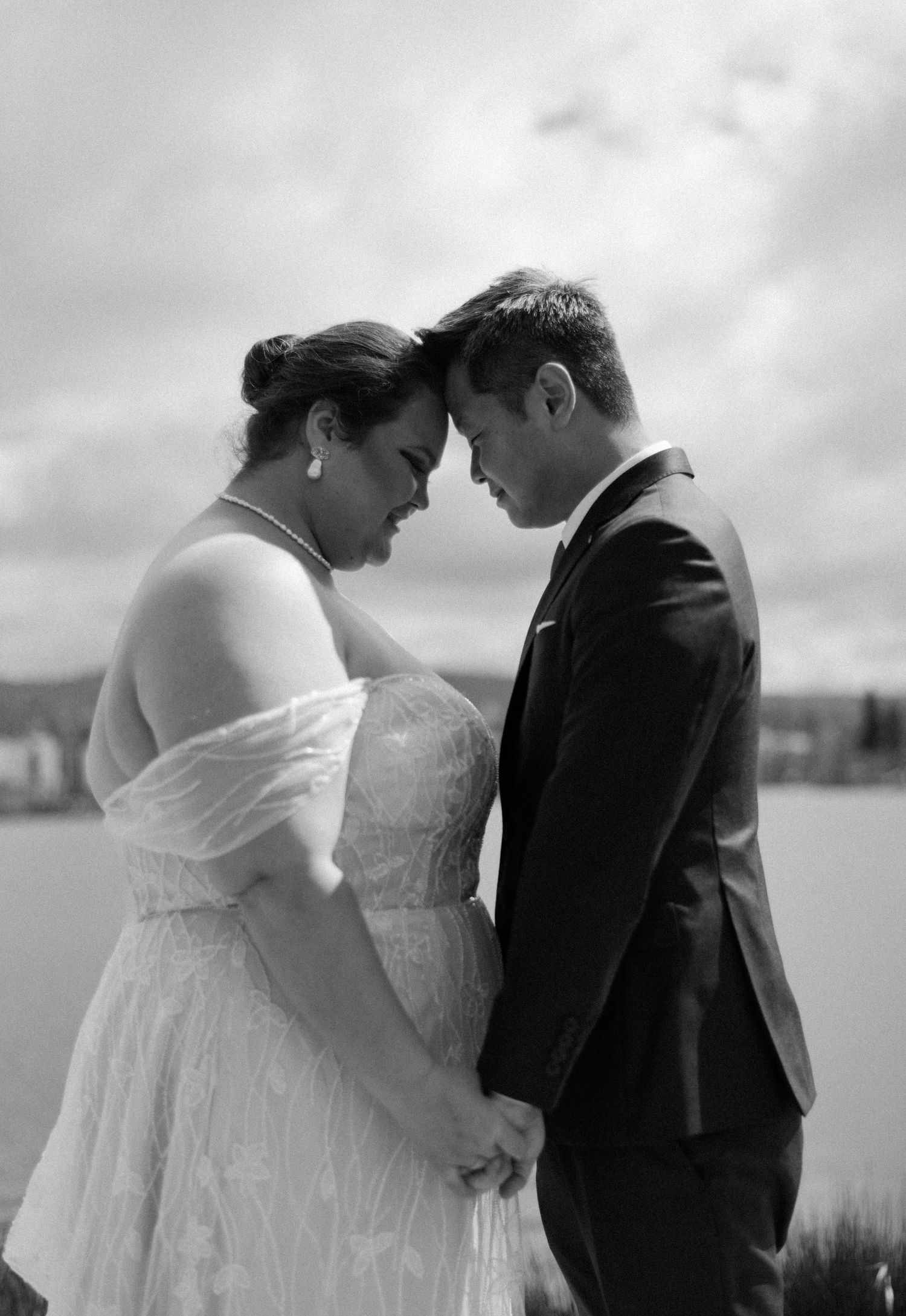 An intimate moment between newlyweds as they touch foreheads in black and white photography.