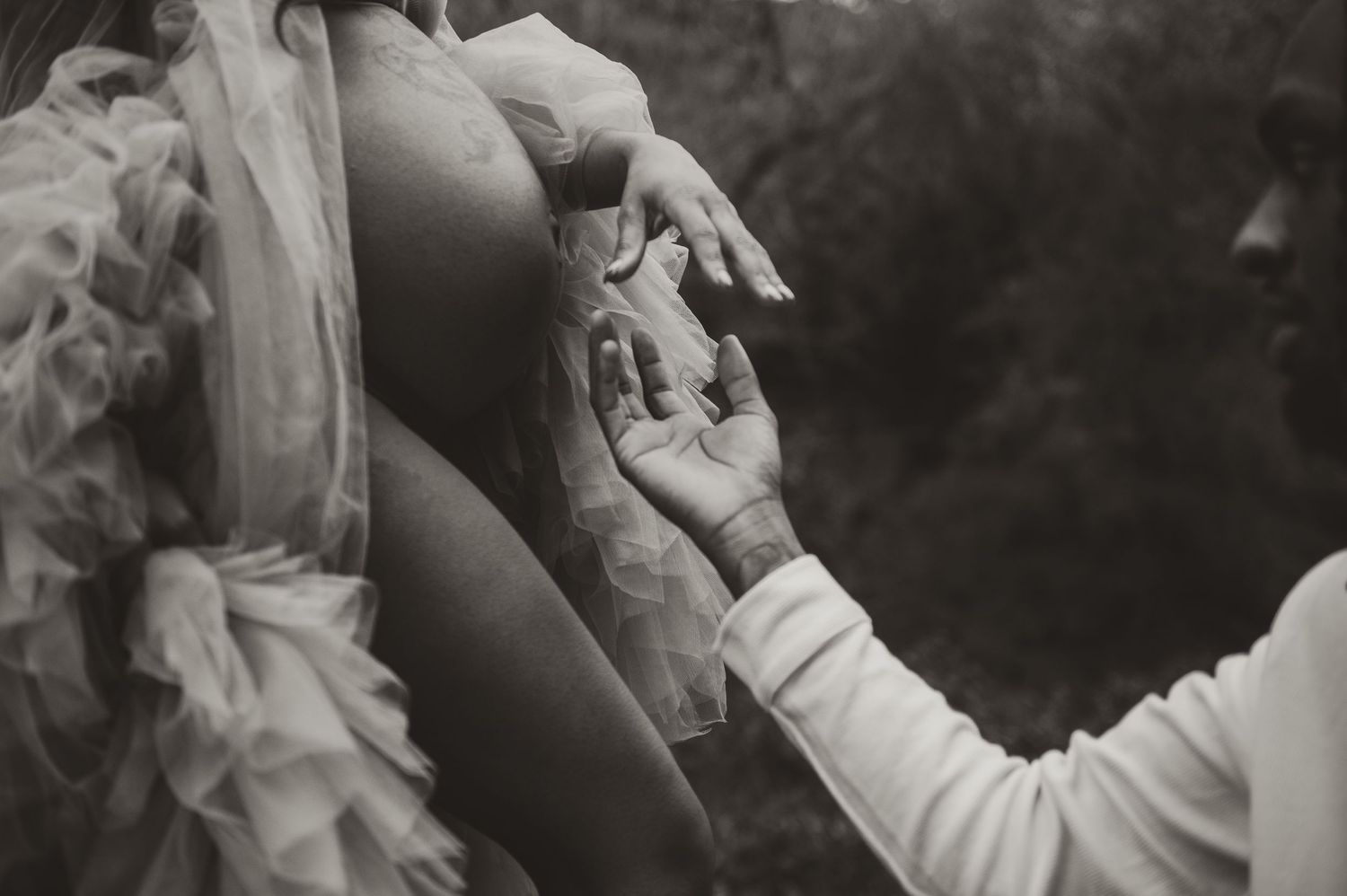 A black and white vintage wedding photo showing hands exchanging rings in an intimate moment.