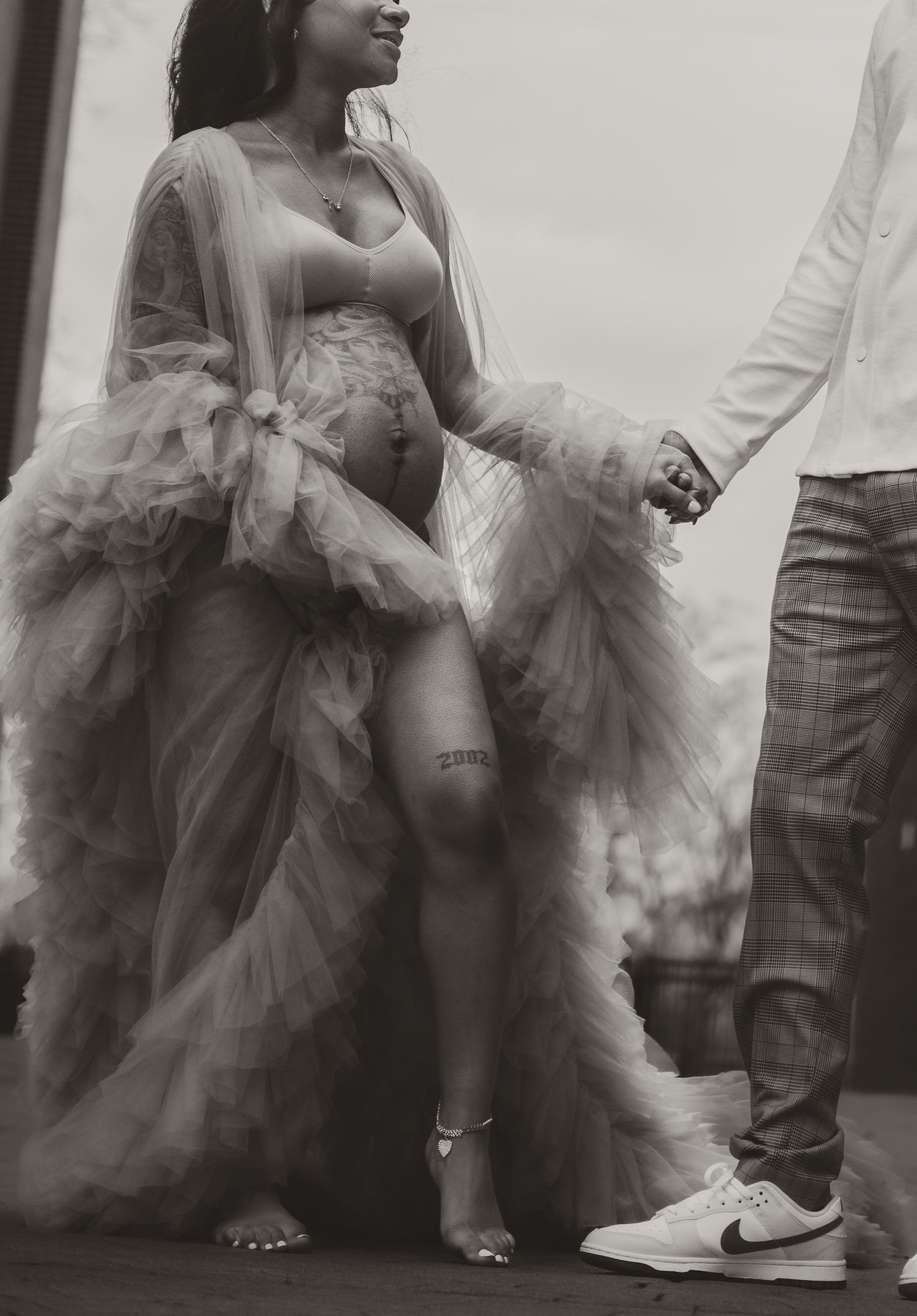 Low angle black and white photo highlighting flowing tulle dress details.