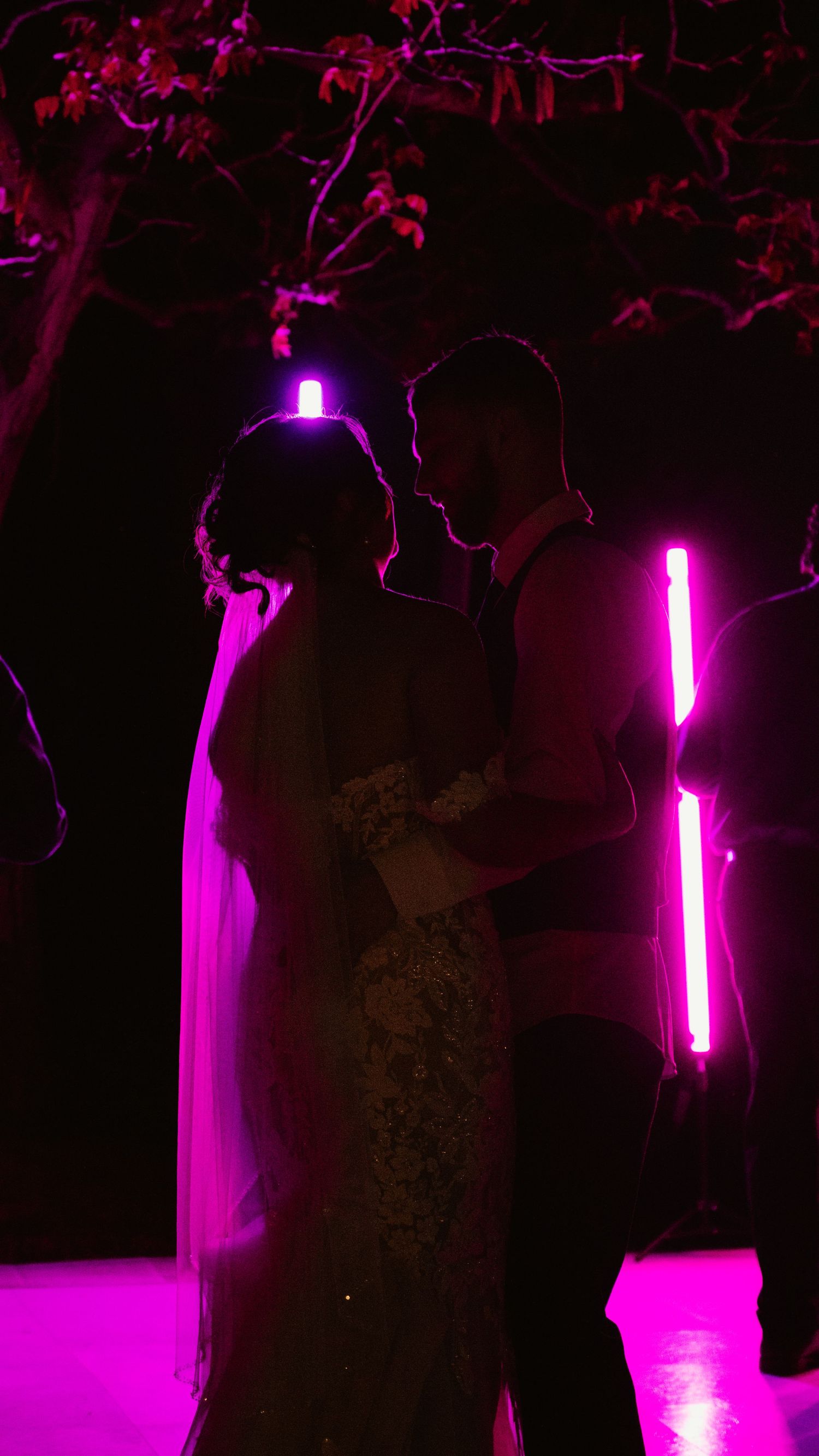 Dance floor illuminated with vibrant purple lighting at nighttime wedding reception.
