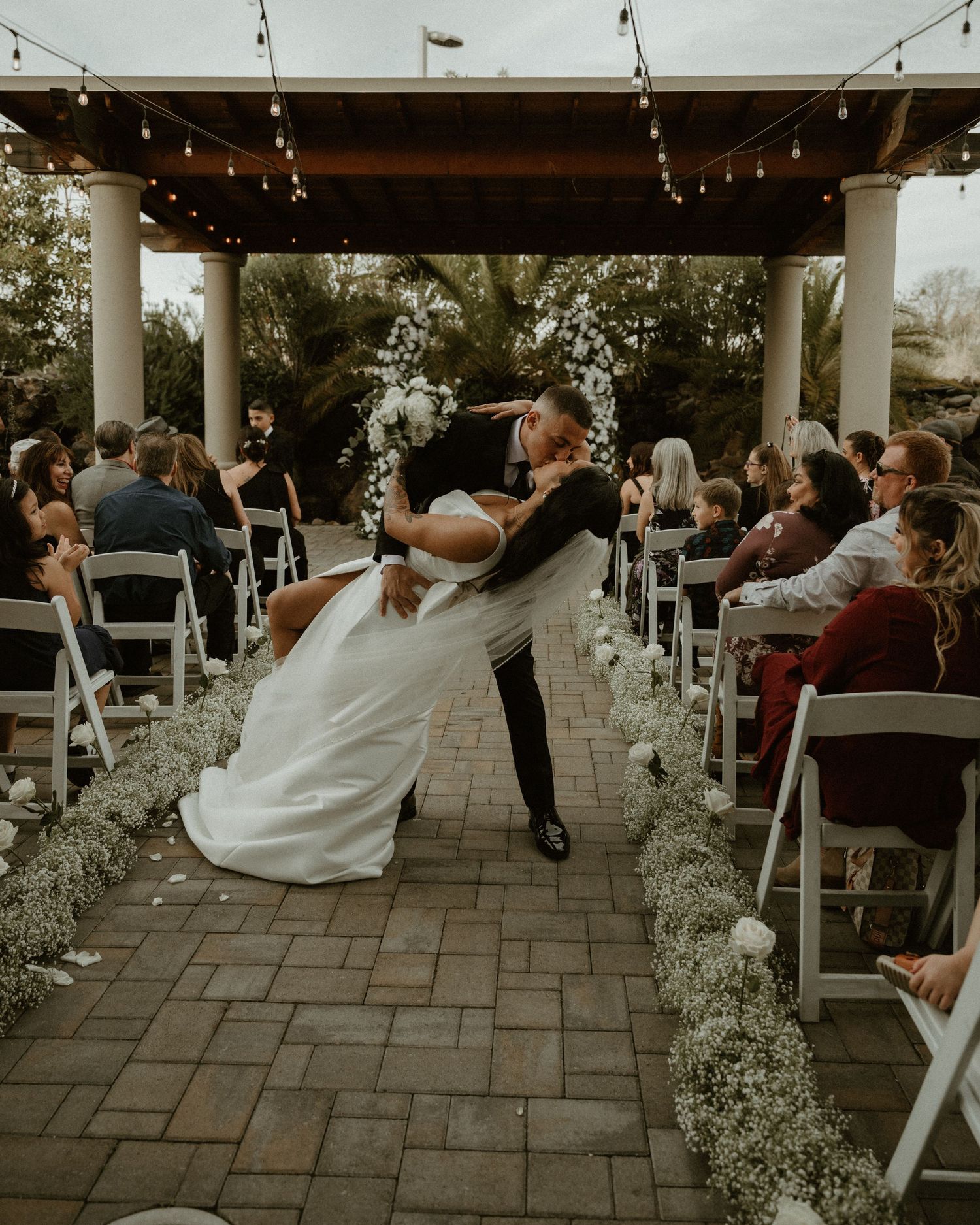 A dramatic dip during the first dance at an outdoor wedding reception under string lights.