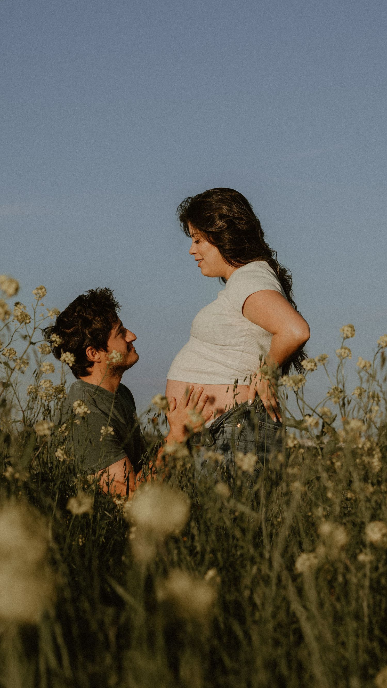 Sunset maternity photo in wildflower field with golden light.