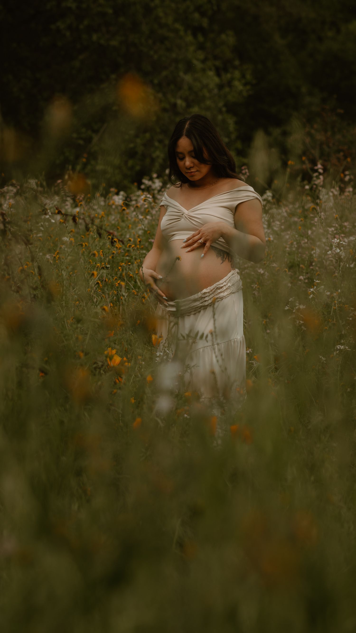 Intimate maternity portrait in a wildflower meadow with soft golden light.
