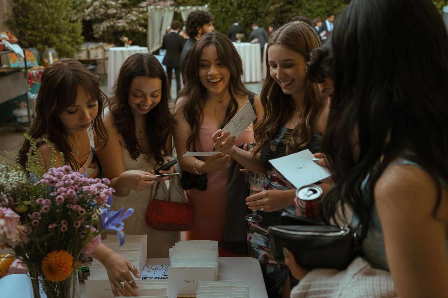 Wedding guests gathering around a guest book table with purple flowers.