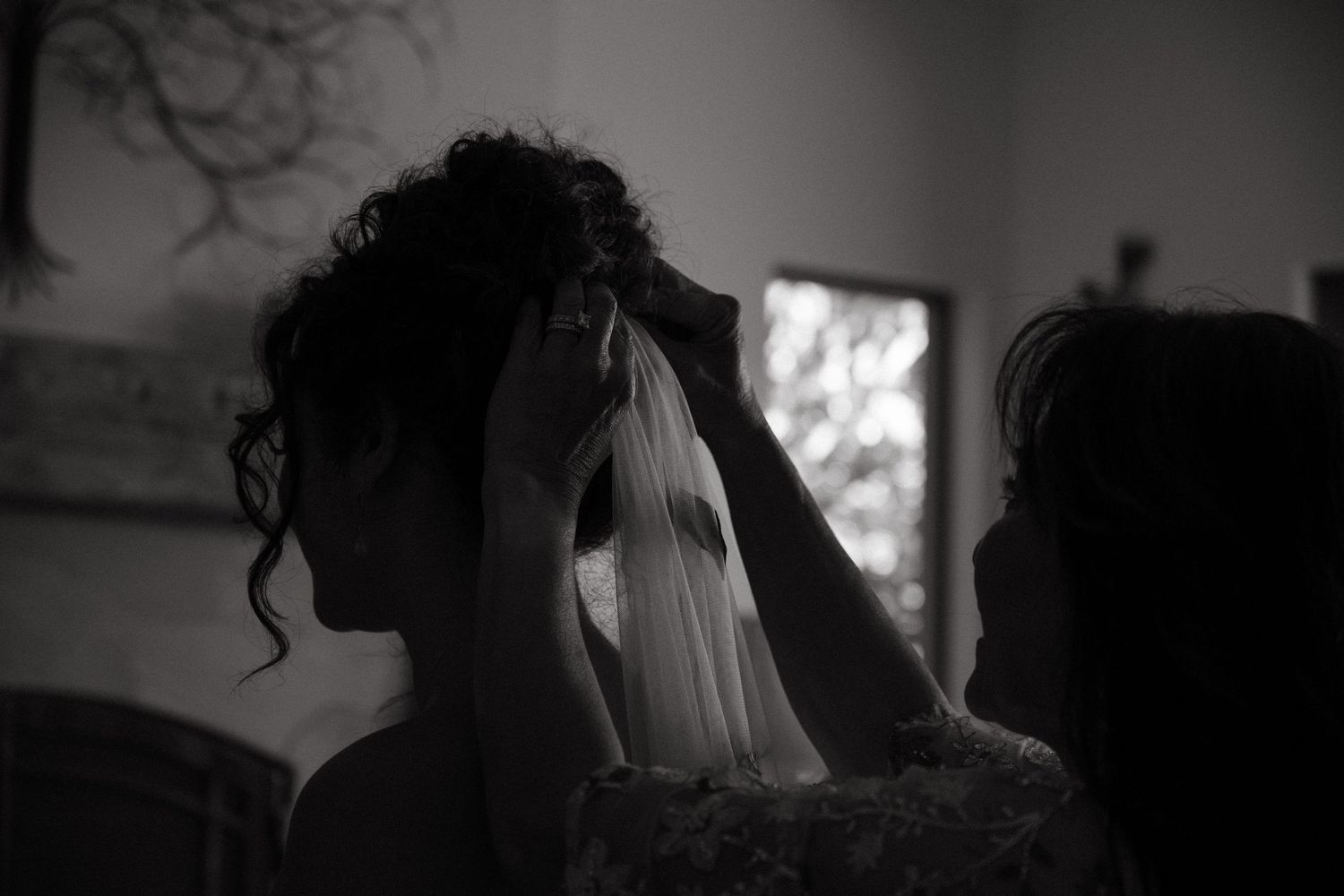 Artistic black and white photo of a bride getting her veil adjusted before the ceremony.